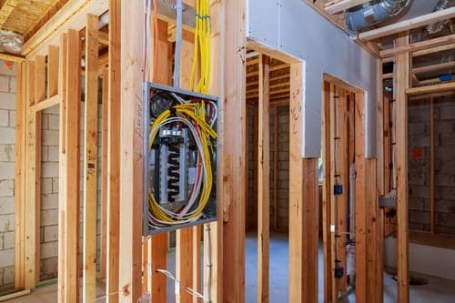 Residential electrical panel mounted in an open wall cavity during a service upgrade