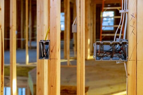 Electrical rough-in wiring and junction boxes installed in the timber framing of a home under renovation